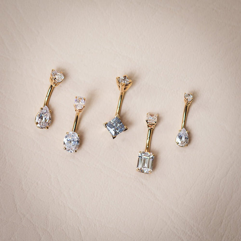 14k yellow gold belly ring collection showing five CZ cuts including emerald, oval, princess, and pear styles