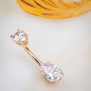 14k rose gold double pear CZ navel ring laid flat near a decorative prop, angled lifestyle shot