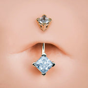 14k gold double princess-cut CZ belly ring shown in pierced navel with light blue lower gem