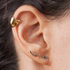 14k gold feather stud worn in lobe piercing, styled with lightning bolt stud and gold helix cuff on model
