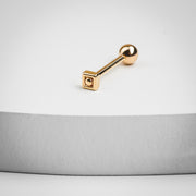 14k rose gold Balinese square labret stud resting on a white surface, side profile showing post length and ball end