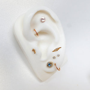 Rose gold yin yang diamond stud worn in helix piercing on ear display with curated ear stack