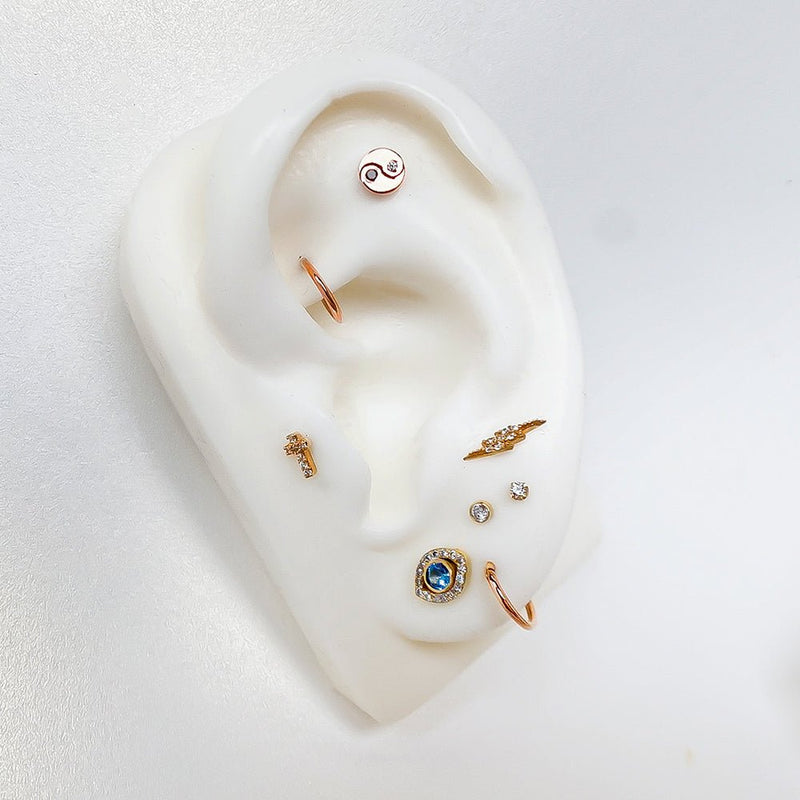 Rose gold yin yang diamond stud worn in helix piercing on ear display with curated ear stack