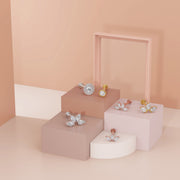 White gold milgrain CZ flat back stud styled alongside gold and rose gold CZ labret studs on pink risers