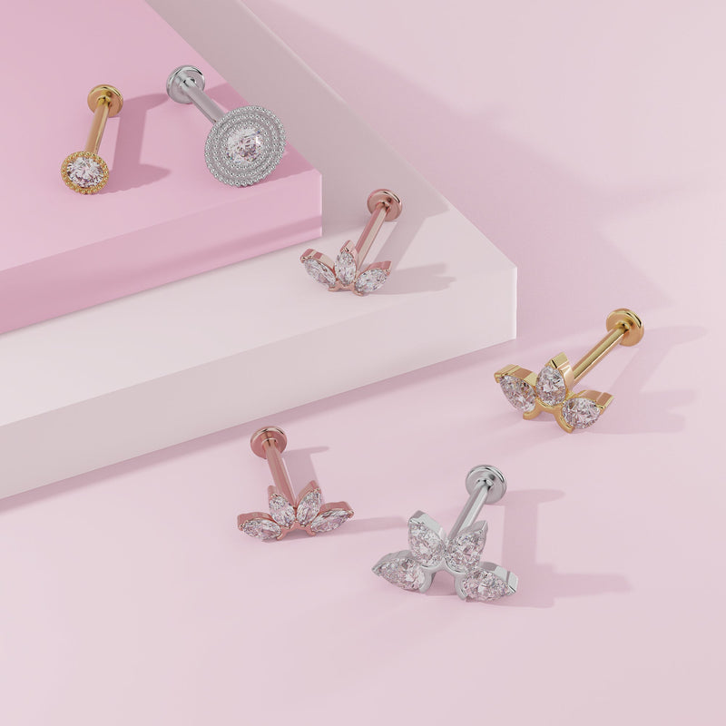 Yellow gold and white gold milgrain CZ labret studs styled alongside other CZ flat back piercing jewelry