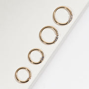 Four 14K yellow gold diamond seam rings in graduated sizes shown on angled white surface