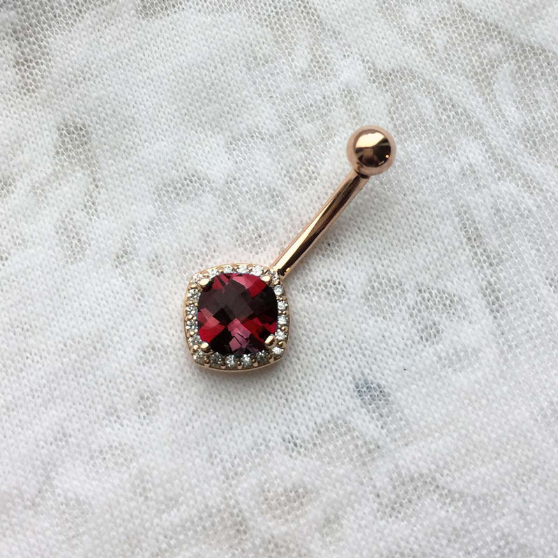 14k rose gold garnet diamond halo navel ring on fabric, showing checkerboard facet detail