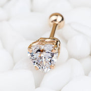14k rose gold heart CZ cartilage earring resting on white pebbles, close-up lifestyle shot