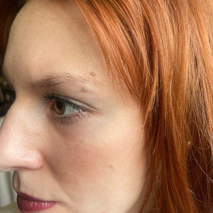 Dainty CZ curved barbell shown in an eyebrow piercing on a model for fit and scale reference