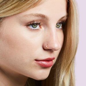 14K gold nose hoop shown in pierced nostril on model, demonstrating fit and delicate scale