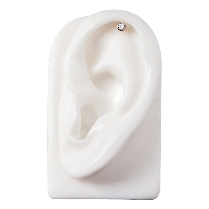 14k gold bezel CZ cartilage stud shown in helix piercing on white ear display, top-down view