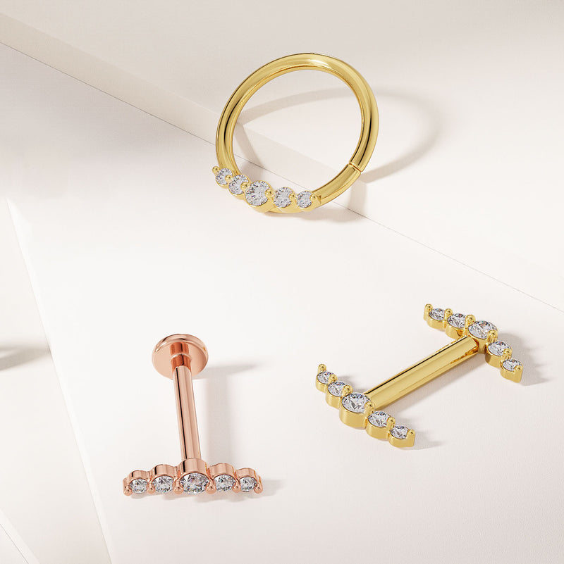 14k gold diamond climber nipple barbell styled alongside matching gold piercing jewelry pieces