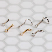 Diamond prong nose studs in yellow and white gold laid flat showing all style options: twist, bone, L post