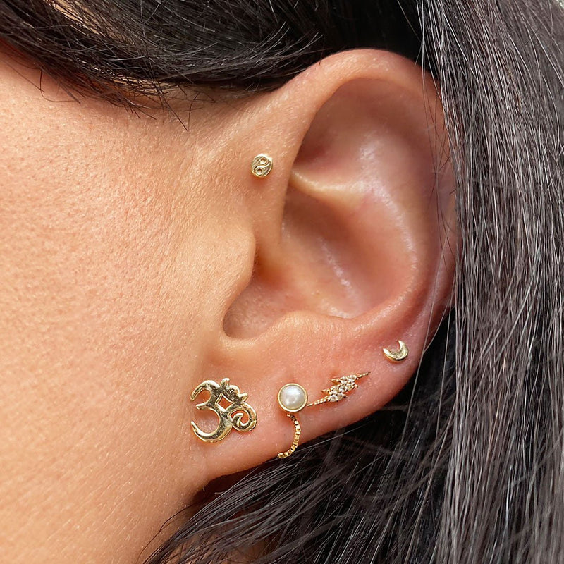 Diamond pavé lightning bolt 14k gold flat back stud worn in lobe piercing as part of curated ear