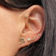 Yellow gold Om ohm flat back stud worn in lobe piercing as part of curated gold ear stack