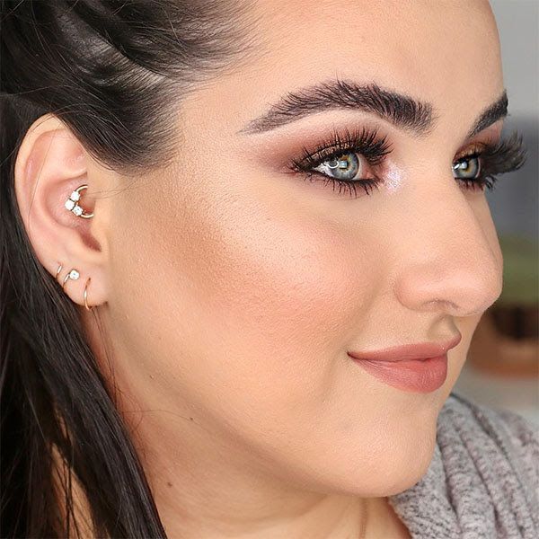 CZ gold clicker ring worn in a daith piercing on a model, shown with coordinating ear jewelry