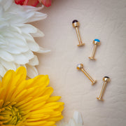 Four 14k yellow gold flat back labrets with cabochon ends including pearl, turquoise, amethyst, and onyx by flowers