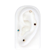 Pearl cabochon flat back stud shown in helix position on white ear display with turquoise, garnet, and onyx variants