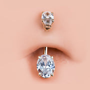 Clear oval CZ 14k gold belly ring shown in navel piercing for fit and scale reference