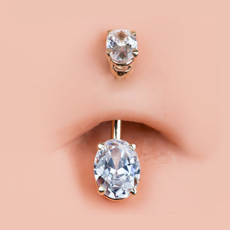 Clear oval CZ 14k gold belly ring shown in navel piercing for fit and scale reference