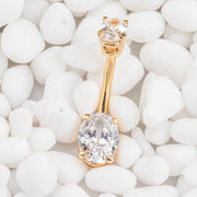 14k yellow gold oval CZ navel ring resting on white pebbles, lifestyle shot