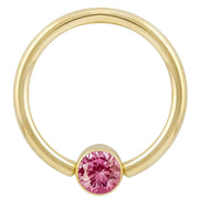 14k yellow gold fixed bead ring with bright pink round-cut CZ in bezel setting, front view