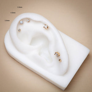 Size comparison of 3mm and 4mm diamond gold flat back studs on white ear display model