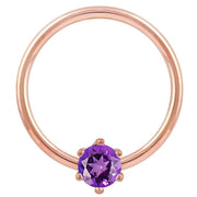 Close-up of 14k rose gold captive ring highlighting purple CZ prong setting and polished band