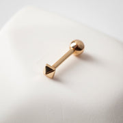 14k rose gold pyramid cartilage stud resting on white surface, side view showing tiny 3mm charm
