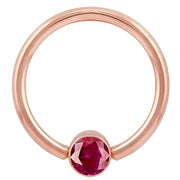 14k rose gold fixed bead ring with red CZ round bezel, angled front view showing warm gold tone