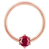 Close-up front view of 14k rose gold captive bead ring with faceted red CZ prong detail