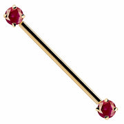 14k yellow gold industrial barbell with dual red CZ prong-set ends, front view on white background