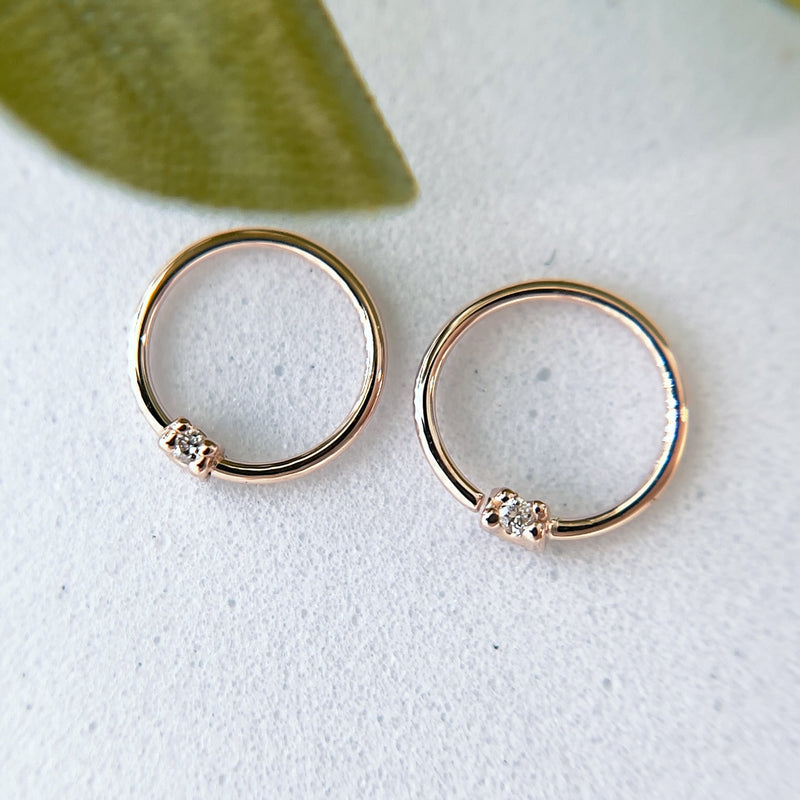 Two 14K rose gold diamond seamless hoop rings side by side on white surface with leaf accent