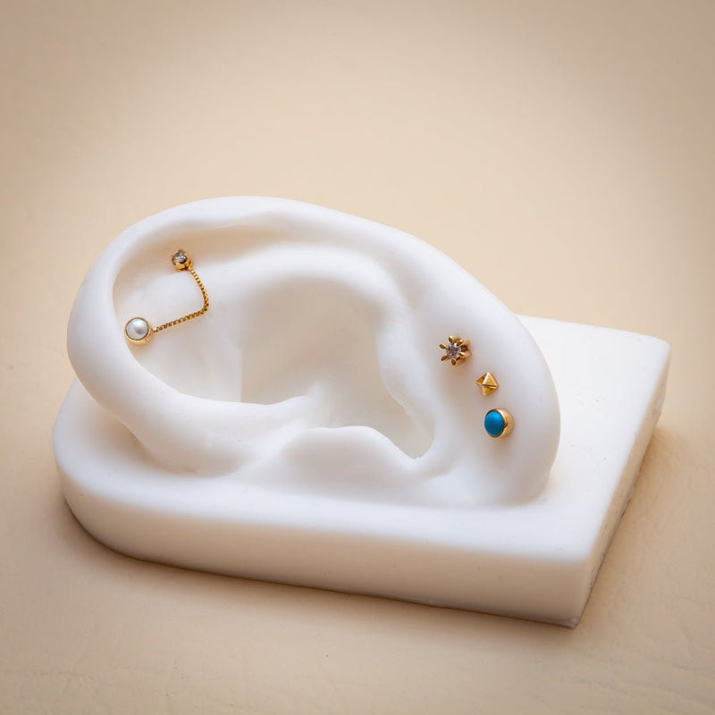 14k gold turquoise cabochon flat back stud shown on ear display with curated piercing stack